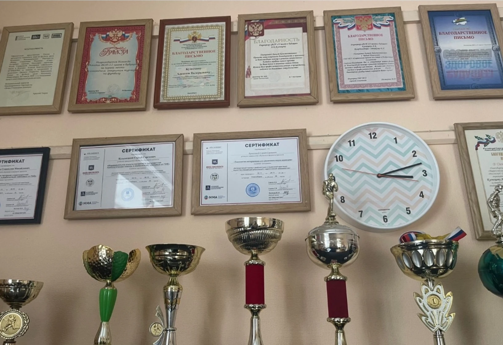 Сертификаты и благодарственные письма в рамках, рядом кубки