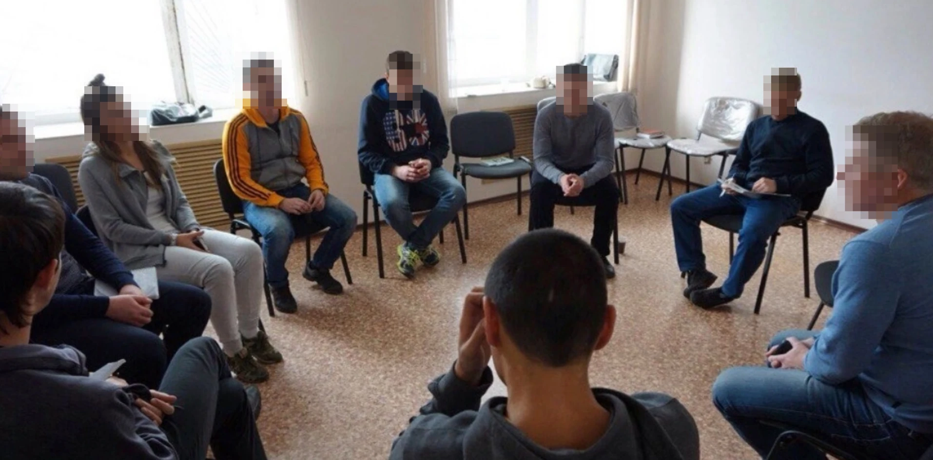Люди сидят в кругу во время групповой встречи; лица скрыты